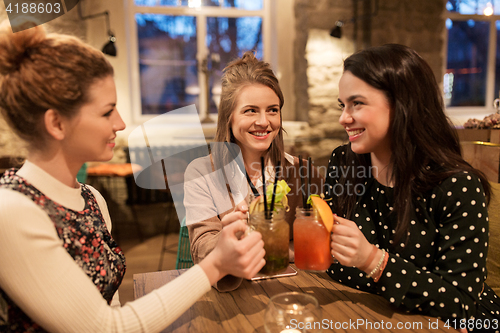 Image of happy friends clinking drinks at restaurant