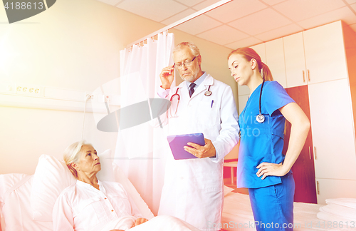 Image of doctor and nurse visiting senior woman at hospital