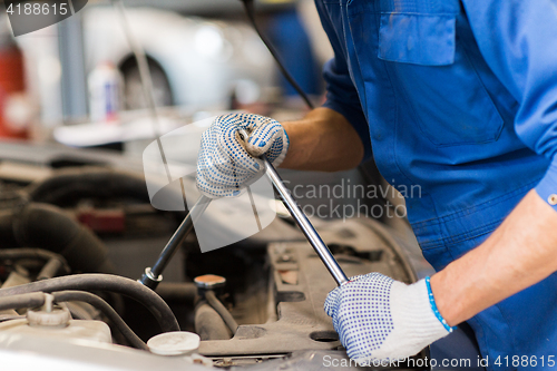 Image of mechanic man with wrench repairing car at workshop