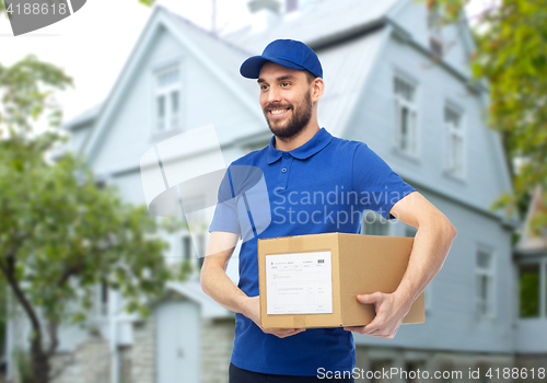 Image of happy delivery man with parcel box over house