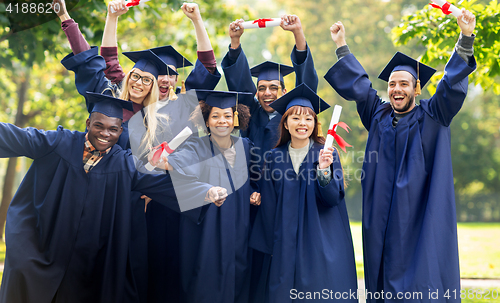 Image of happy students in mortar boards with diplomas