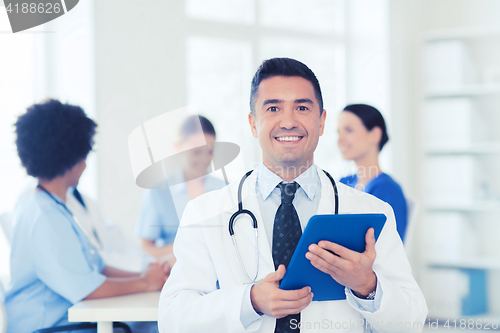 Image of happy doctor with tablet pc over team at clinic