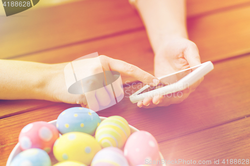 Image of close up of hands with easter eggs and smartphone