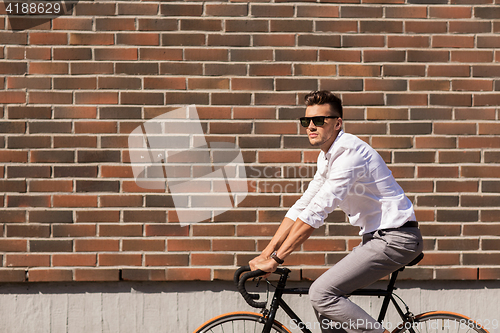 Image of young man riding bicycle on city street