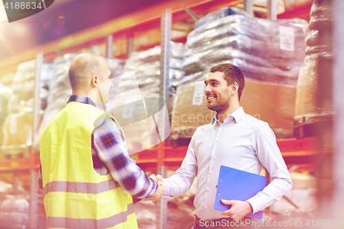 Image of worker and businessmen with clipboard at warehouse