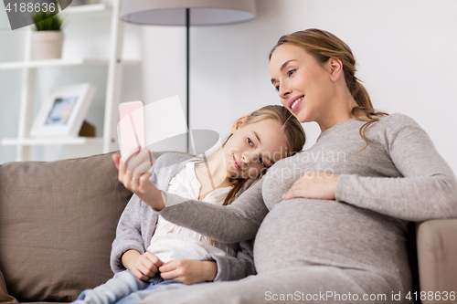 Image of pregnant woman and girl taking smartphone selfie