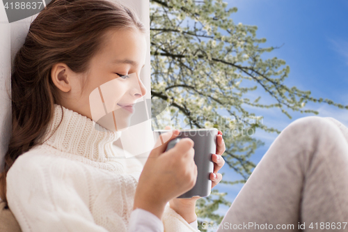 Image of girl with tea mug sitting at home window