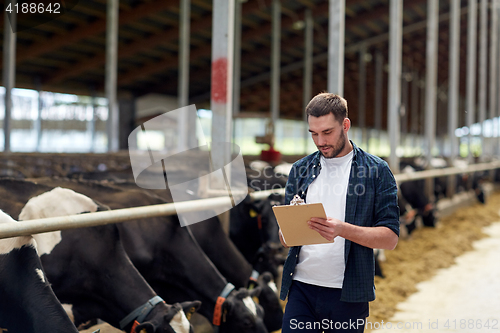 Image of farmer with clipboard and cows in cowshed on farm