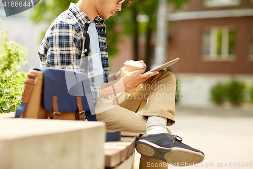 Image of man with tablet pc and coffee on city street bench