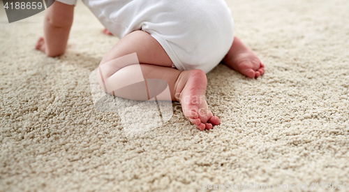 Image of little baby in diaper crawling on floor at home