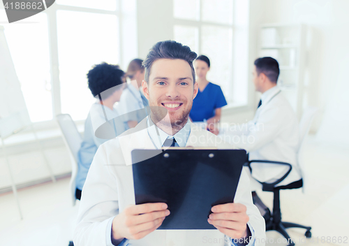 Image of happy doctor with tablet pc over team at clinic