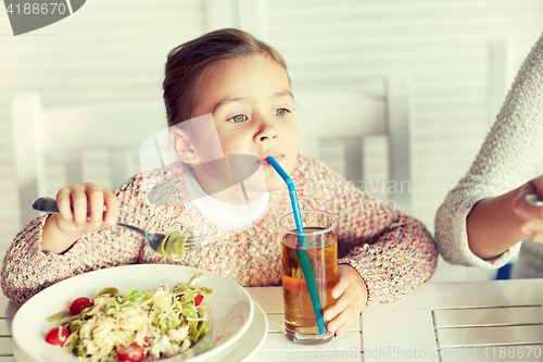 Image of little girl drinking apple juice at restaurant
