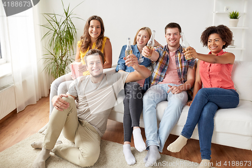 Image of happy friends with popcorn and beer at home