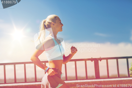 Image of smiling young woman running outdoors