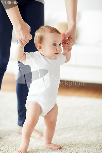 Image of happy baby learning to walk with mother help