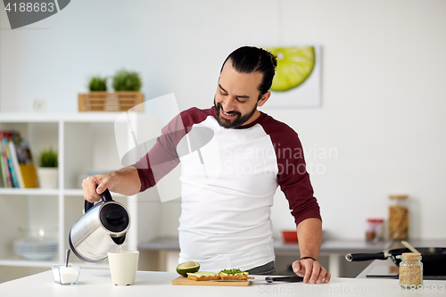 Image of man with kettle making tea for breakfast at home