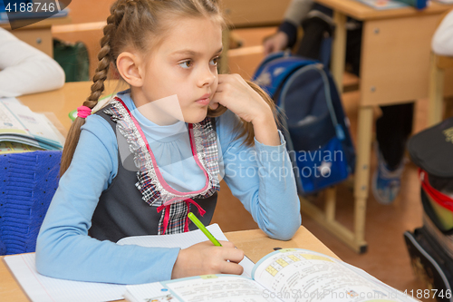 Image of Girl schoolgirl sits at a school desk at a lesson at school