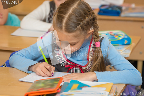 Image of First-grader at a lesson of mathematics to solve the examples notebook