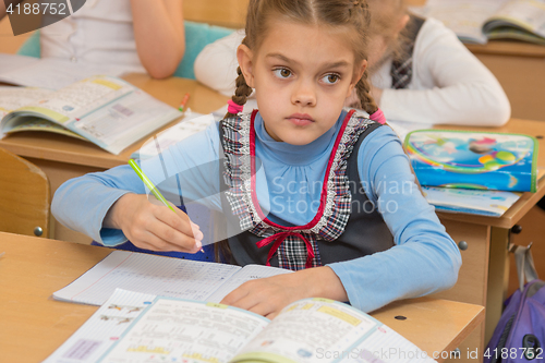 Image of First-grader at a lesson of mathematics solves examples and look at the board