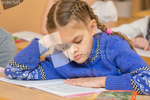 Image of First grader at reading lesson reading text sitting at a school desk