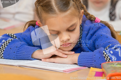 Image of First grader to read the lesson reads the text in the book with his head in his hands