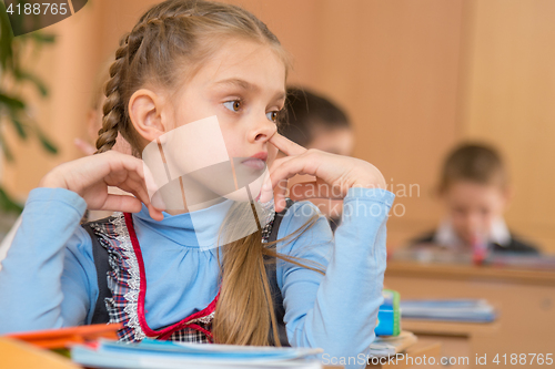 Image of The girl at a lesson at school picking his nose