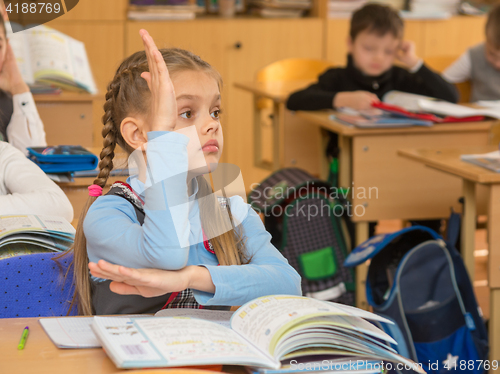 Image of Girl schoolgirl at a lesson at school wanting to pull your hand up to answer a question