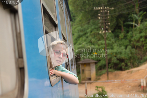 Image of Blonde caucasian woman riding a train, looking trough window.