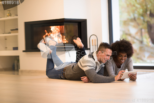 Image of multiethnic couple used tablet computer on the floor