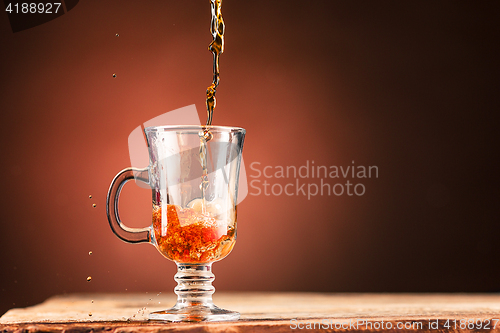 Image of Brown splashes out drink from cup of tea on a brown background