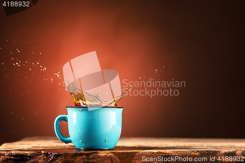 Image of Brown splashes out drink from cup of tea on a brown background