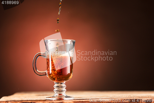 Image of Brown splashes out drink from cup of tea on a brown background