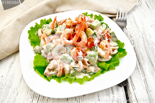 Image of Salad with shrimp and avocado in white plate on light board