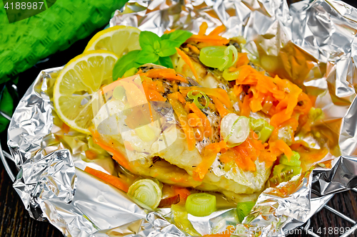 Image of Pike with carrots and basil in foil on board