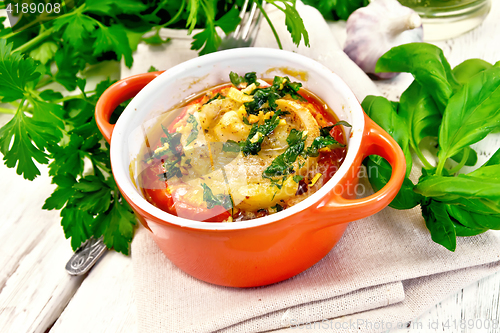 Image of Fish baked with tomato and basil in red pot on board