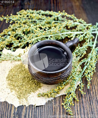 Image of Tea with wormwood in cup on dark board