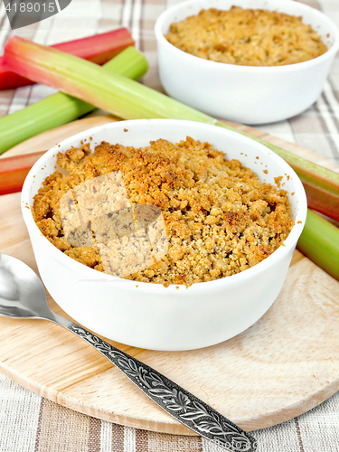 Image of Crumble rhubarb in white bowl on linen tablecloths