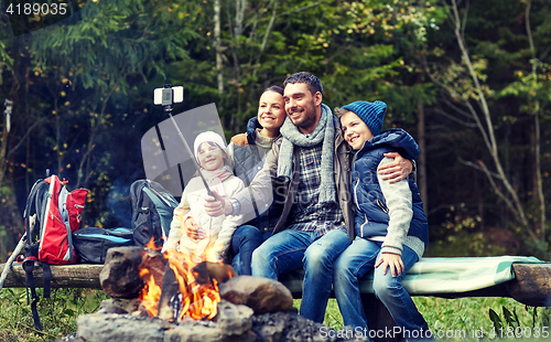 Image of family with smartphone taking selfie near campfire