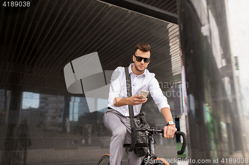 Image of man with bicycle and smartphone on city street