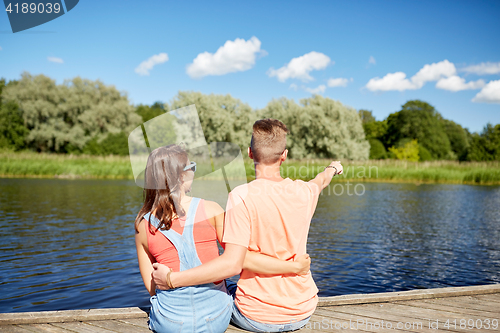 Image of happy couple pointing finger on summer river berth