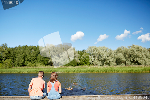 Image of couple on river berth looking at swimming ducks