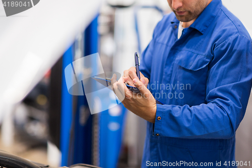 Image of auto mechanic with clipboard at car repair shop