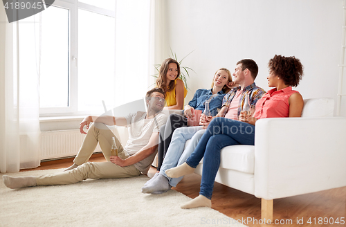 Image of happy friends with popcorn and beer at home