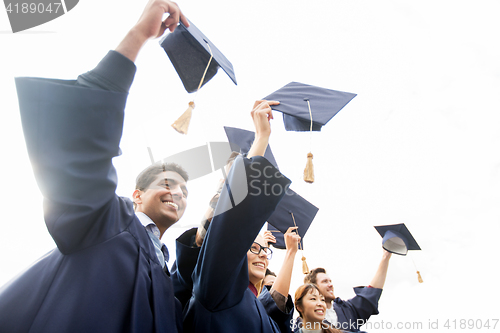 Image of happy students or bachelors waving mortar boards