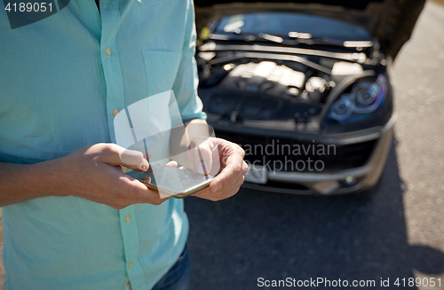 Image of close up of man with smartphone and broken car