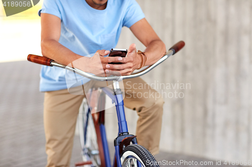 Image of close up of man with smartphone and bike on street