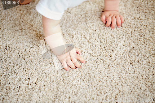 Image of hands of baby crawling on floor or carpet