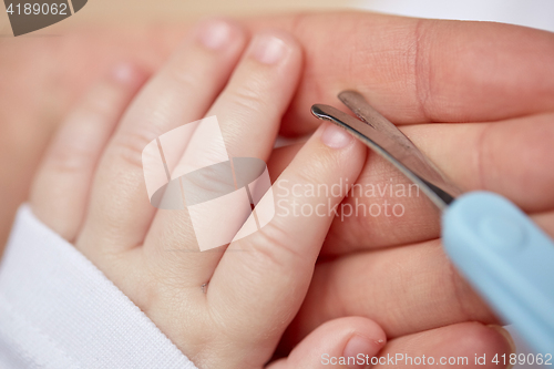 Image of close up of hand with scissors trimming baby nails