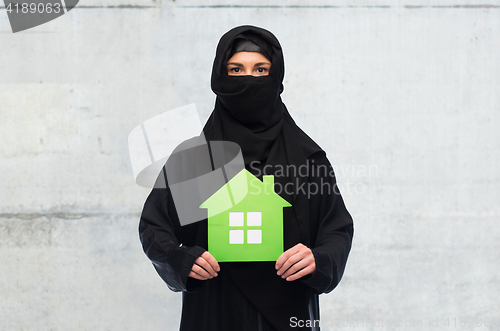 Image of muslim woman in hijab with green house over white