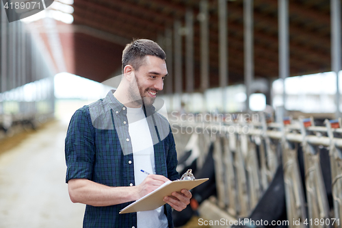 Image of farmer with clipboard and cows in cowshed on farm